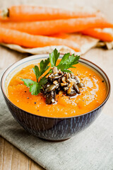 Bowl of carrot soup with sesame and pumpkin seeds and parsley garnish