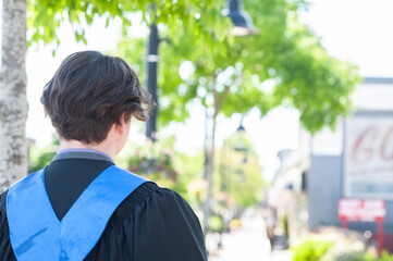 Young school graduate walks down the sidewalk