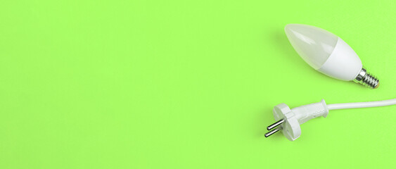 Saving energy, eco concept. LED light bulb and electrical power cable, green background, banner, top view and flat lay with copy space