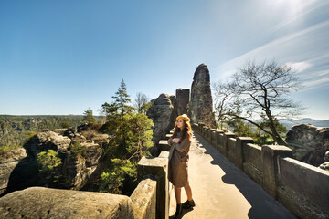 a girl in a grey coat and hat on a bridge in Saxon Switzerland, Germany, Bastei.