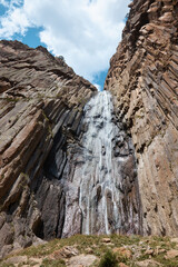 Fototapeta na wymiar high waterfall, cliff and rocks, bottom view of a mountain waterfall, nature, landscape in the mountains