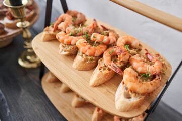 Delicious fresh seafood, shrimp with fresh vegetables. buffet table with lots of delicious snacks. canapes, bruschetta, and little desserts on wooden plate board