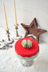 Mousse cake covered with red velour. Dessert on a snow-covered table. Modern european cake. French cuisine. Christmas theme. Copy space