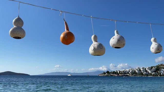 Handmade decorative lamps of calabash gourd hanging and swaying in the wind against the background of the sea and sky. High quality 4k footage
