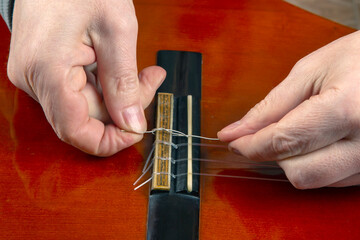 Replacing and tuning nylon strings on a six-string classical guitar. instruction for musician