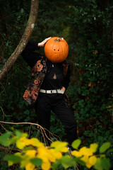 person with a pumpkin on their head leaning on a tree