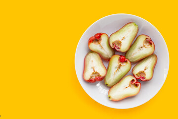 Fresh rose apple in white plate on yellow background.