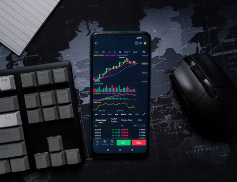 phone with stocks on screen on top of desk - Powered by Adobe