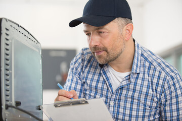 serviceman writing the appliance serial number on his paperwork