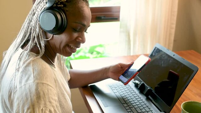 Video de primer plano de una mujer afroamericana utilizando el celular y unos auriculares 