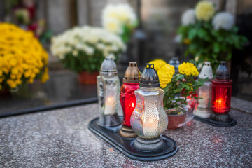 candles and white flowers on the tomb on All Saints' Day
