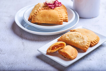 Empanadillas rellenas de atun con tomate y cebolla sobre un fondo blanco.