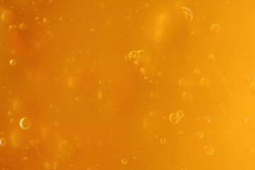 Texture of transparent yellow antiseptic gel with air bubbles. Skin moisturizing concept and prevention of Covid. Beauty product closeup. Liquid honey. Backdrop, flat lay, macro. Abstract background