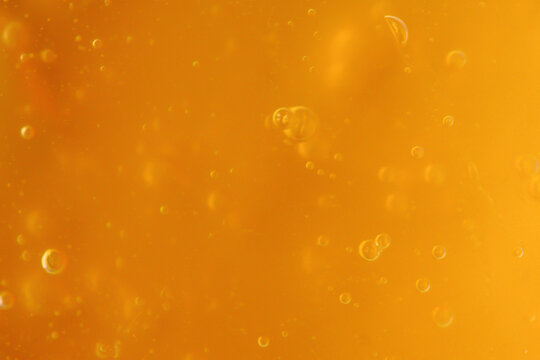 Texture of transparent yellow antiseptic gel with air bubbles. Skin moisturizing concept and prevention of Covid. Beauty product closeup. Liquid honey. Backdrop, flat lay, macro. Abstract background