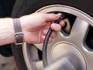 Hands of a man and an automatic pump or compressor for inflating car tires at a service station, close-up, soft focus.