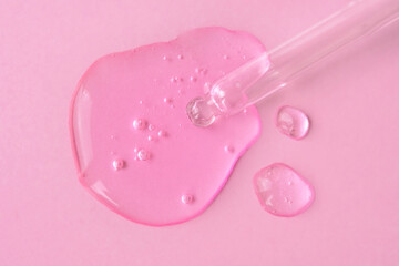 Pipette with fluid hyaluronic acid on pink background. Cosmetics and healthcare concept closeup. Dose of serum or retinol with air bubbles. Top view. Luxury gel or beauty product presentation in macro