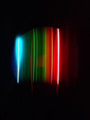 Vertical shot of neon streaks of lights on a black background