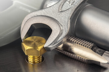 Wrench tightens brass bolt in steel billet. Spanner, bolt, screw and nuts.
