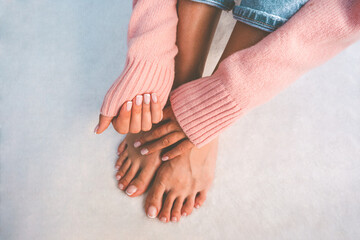 Stilvolle Frau im rosafarbenen Pullover, die ihre schönen Nägel mit französischer Maniküre und Pediküre zeigt. Nägel nach Maniküre- und Pedikürebehandlung. Platz kopieren