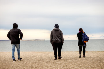 Three tourists watch southern right whales at El Doradillo beach, near Puerto Madryn, Argentina