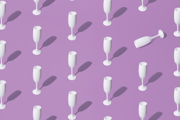Arranged white champagne glasses on purple pastel background. Minimal pattern and concept.
