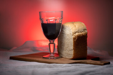 glass of wine and bread. representation of the Holy Supper. front image with red background