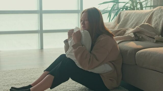 Frustrated Red haired Teenage Girl Sitting on the Floor. A Sad Teenager Feels Anxiety, Stress, Shame, Fear. Teenage Psychological Trauma, Cyberbullying. Mental Health.