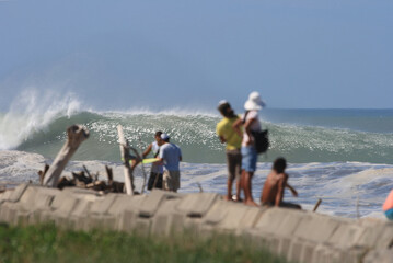 group of people and surfers watching large waves