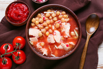 Bowl with delicious pozole soup and ingredients on table