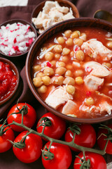 Tasty pozole soup in bowl and ingredients on table, closeup