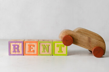 Word RENT with wooden car on white background