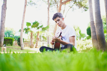 Ethnic teen playing guitar on grass