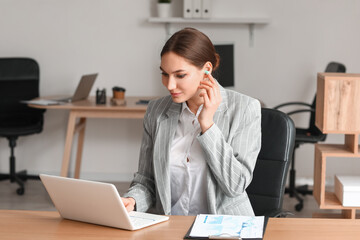 Young woman with earplugs working in office