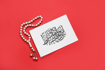 Fototapeta na wymiar Paper with Arabic text and tasbih on color background