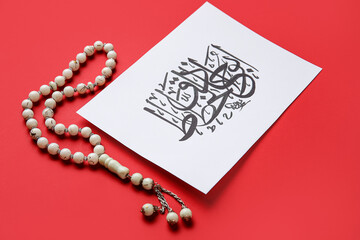Paper with Arabic text and tasbih on color background