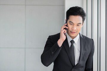 Businessman standing contemplating while use mobile phone