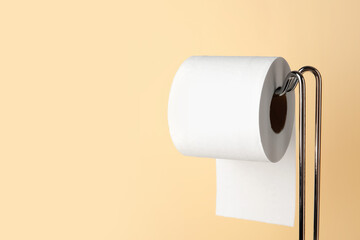 Modern holder with toilet paper roll on beige background, closeup