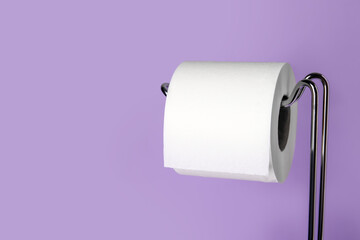 Holder with toilet paper roll on purple background, closeup