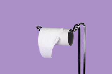 Holder with cardboard tube for toilet paper on purple background, closeup