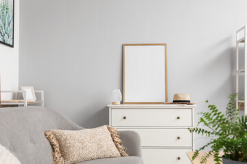 Blank poster frame on chest of drawers in light living room