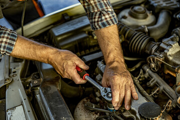 Repairman's male hands with a wrench. Vehicle fitter inspecting used car engine