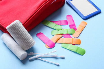 First aid kit and blank identification badge on blue background, closeup