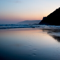 Obraz premium Disappearing footprints emerge from beach. Sunset along Great Ocean Road