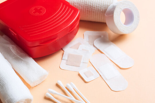 First aid kit with medical plasters, elastic bandage and cotton buds on color background, closeup