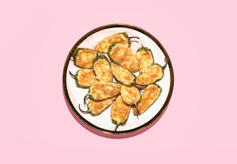 Plate with tasty jalapeno poppers on pink background