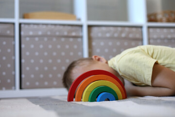 Boy plays and assembles puzzle of colored wooden geometric shapes at Montessori school. Home education