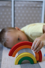 Boy plays and assembles puzzle of colored wooden geometric shapes at Montessori school. Home education