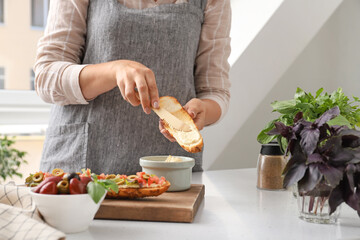 Woman spreading toast with dip at table in kitchen