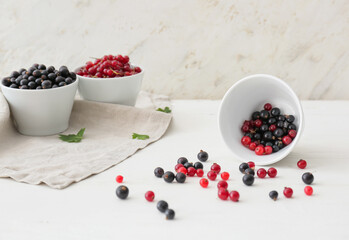 Bowl with tasty red and black currant on light background