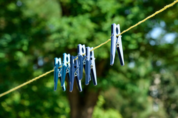 Many clothespins hanging on laundry line outdoors, closeup